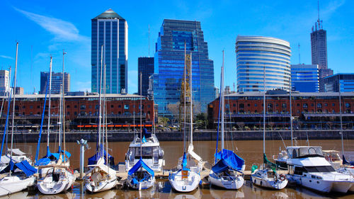 Boats moored at harbor against buildings in city