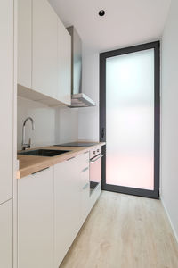 A small new kitchen with oven, stove and extractor. interior with  cabinets and wooden counter top.