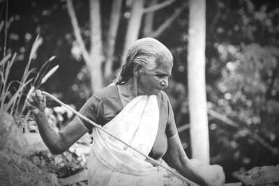 Senior woman with rope standing outdoors