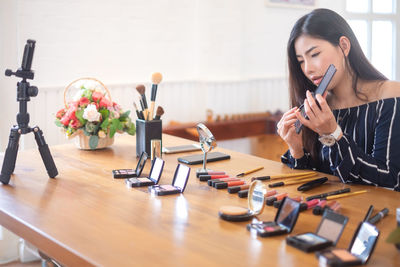 Young woman using phone while sitting on table