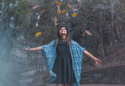 Happy young woman standing by tree in water