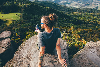 Rear view of woman sitting on rock