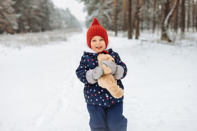 Candid portrait of cute little girl having fun playing outdoor during snowfall.