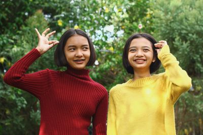 Smiling teenage friends looking away while standing against plants