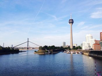 Low angle view of tower by river against sky in city