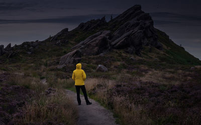 Rear view of man standing on mountain against sky