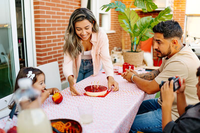 Smiling family celebration. kids and father are happy that food arrived. dad serves pasta dish.