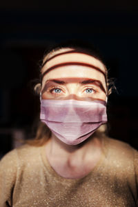 Portrait of young woman wearing mask in darkroom