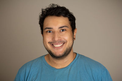 Portrait of smiling young man against gray background