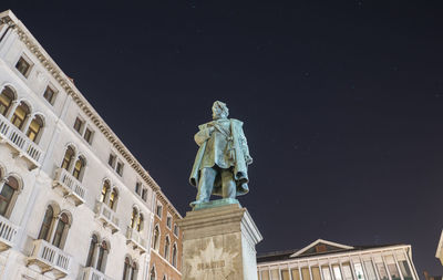 Low angle view of statue against building at night