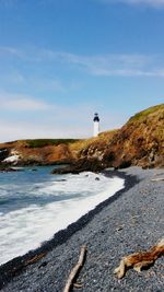 Lighthouse by sea against sky