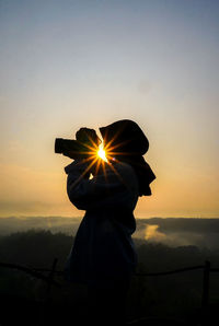 Silhouette man standing against sky during sunset