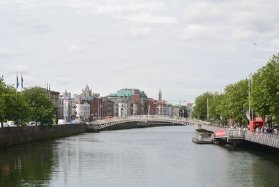 Bridge over river in city against sky