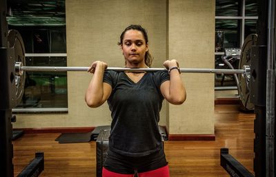 Determined young woman lifting barbell at gym