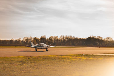 Airplane on airport runway against sky