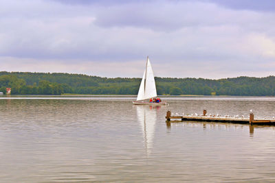 Sailboat sailing on lake against sky