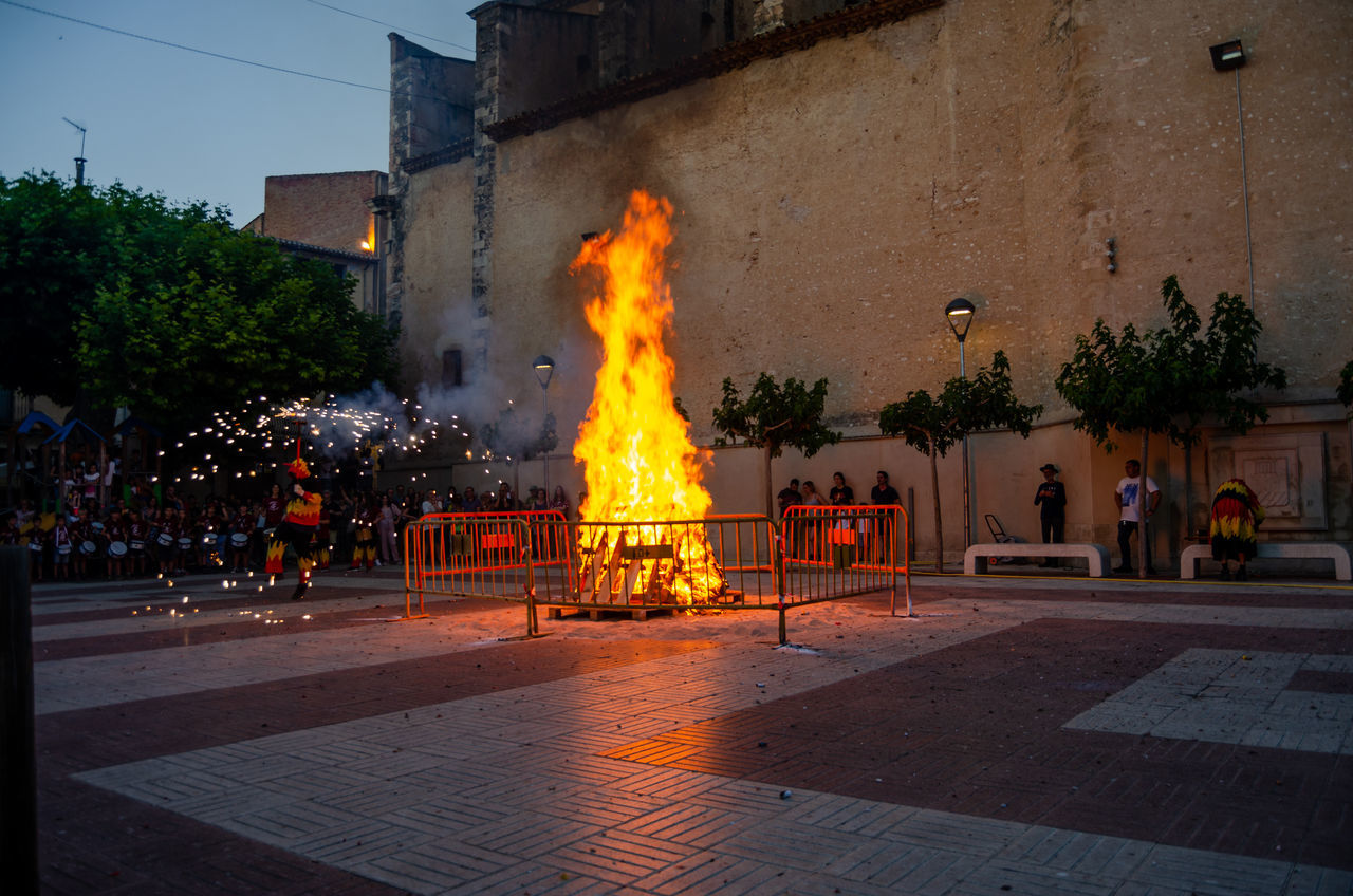 architecture, fire, burning, building exterior, built structure, city, flame, street, nature, night, heat, tree, plant, evening, building, sign, outdoors, group of people, illuminated, tradition