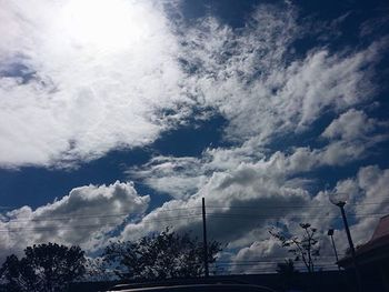 Low angle view of power lines against cloudy sky