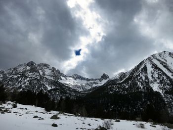 Scenic view of snow covered mountains against cloudy sky