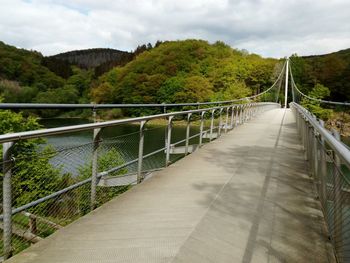 Footbridge over mountain against sky