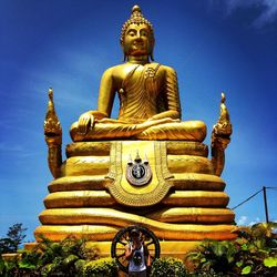 Low angle view of statue against temple building against sky