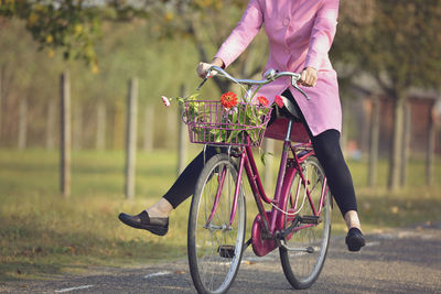 Low section of woman riding bicycle on road