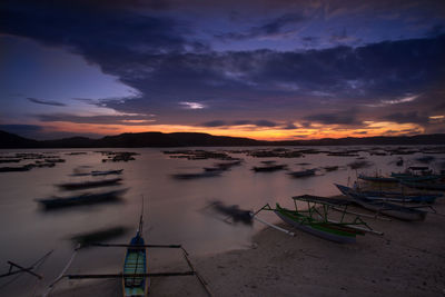 Boats moored in sea against sky during sunset