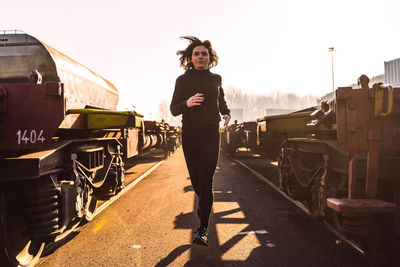 Young adult woman is running in the morning between two rows of wagons