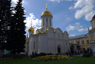 Church amidst trees and buildings against sky