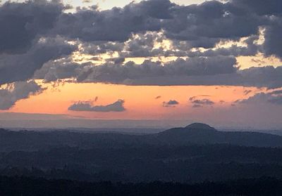 Scenic view of mountains against dramatic sky during sunset