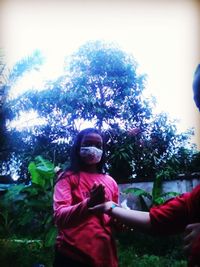 Man and woman standing by tree against sky