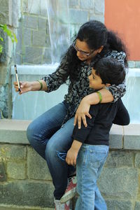 Woman taking selfie with son at retaining wall
