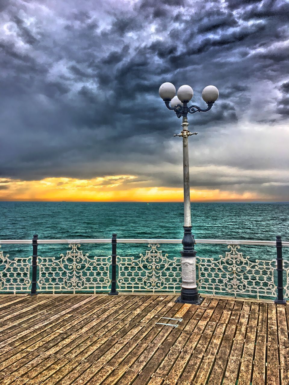 STREET LIGHTS ON PIER OVER SEA AGAINST SKY