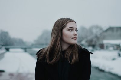 Close-up of young woman standing against lake during winter