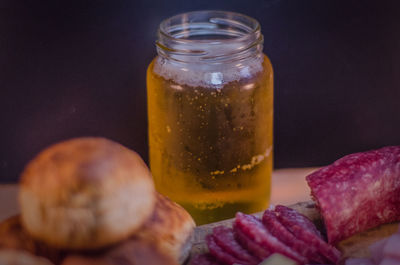 Close-up of beer in jar with bread and sliced salami on table