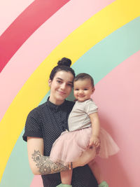 Portrait of mother and daughter against multi colored background