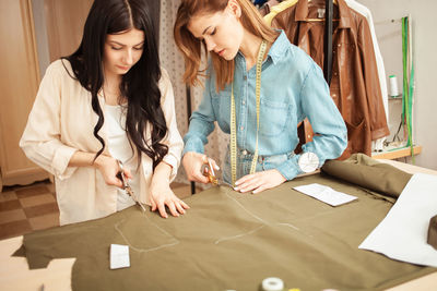 Seamstresses cut out from fabric details of future clothes, pattern. fashionable sewing studio, 