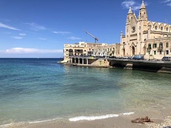 View of building by sea against blue sky