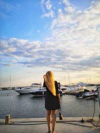 Rear view of woman standing at harbor against sky