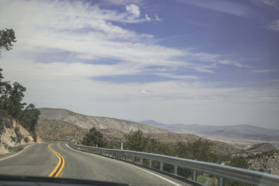 Road leading towards mountains against sky