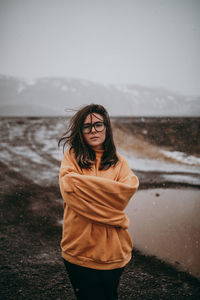 Young happy tourist in eyeglasses with piercing looking at camera between deserted ground in snow