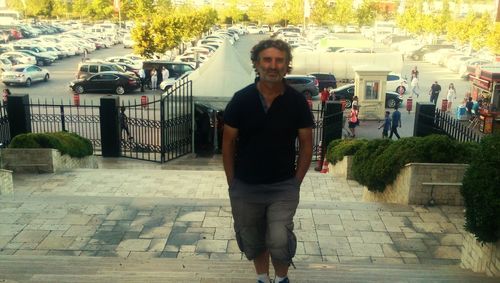 Portrait of young man standing on footpath in city