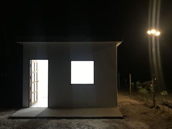 View of illuminated electric lamp against wall at night