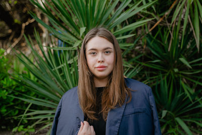 Portrait of young woman standing amidst plants
