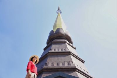 Woman sitting at temple against sky