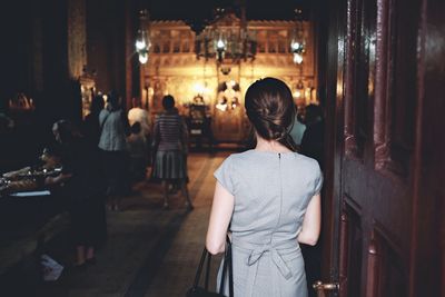 Rear view of woman standing by door at church