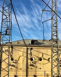 Low angle view of electricity pylon against buildings