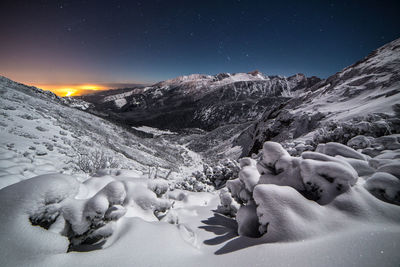 Scenic view of snow covered mountains against sky at night