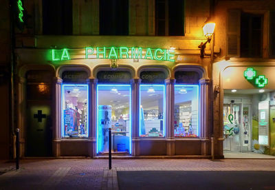 Illuminated restaurant by street in city at night