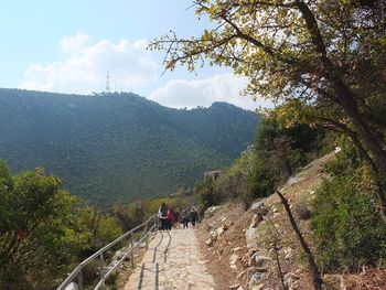 Rear view of people walking on mountain against sky